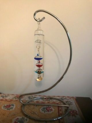 Galileo Glass Thermometer With Floating Spheres On A Metal Stand.