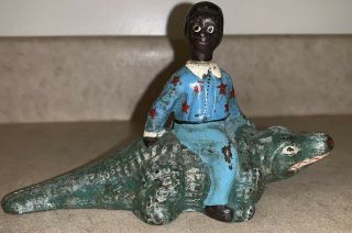 Antique Cast Iron Black Americana Man Riding An Alligator Blue Shirt Red Stars