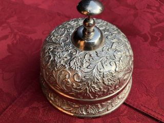 An Antique Style Circular Table Top Bell In A White Metal With Push Top