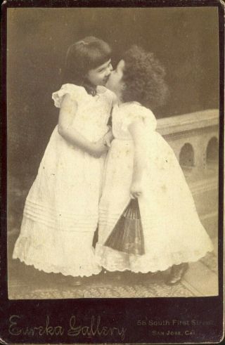 Antique Photographs On Card Of Two Toddler Girls Kissing One Holding A Paper Fan